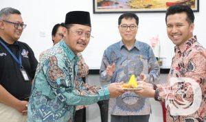 Ketua KPPU RI M. Afif Hasbullah memberikan potongan tumpeng kepada Wakil Gubernur Jawa Timur Emil Dardak
